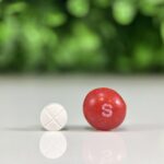 GS-441524 quad tablet compounded for cats shown next to a Skittles candy for size comparison.